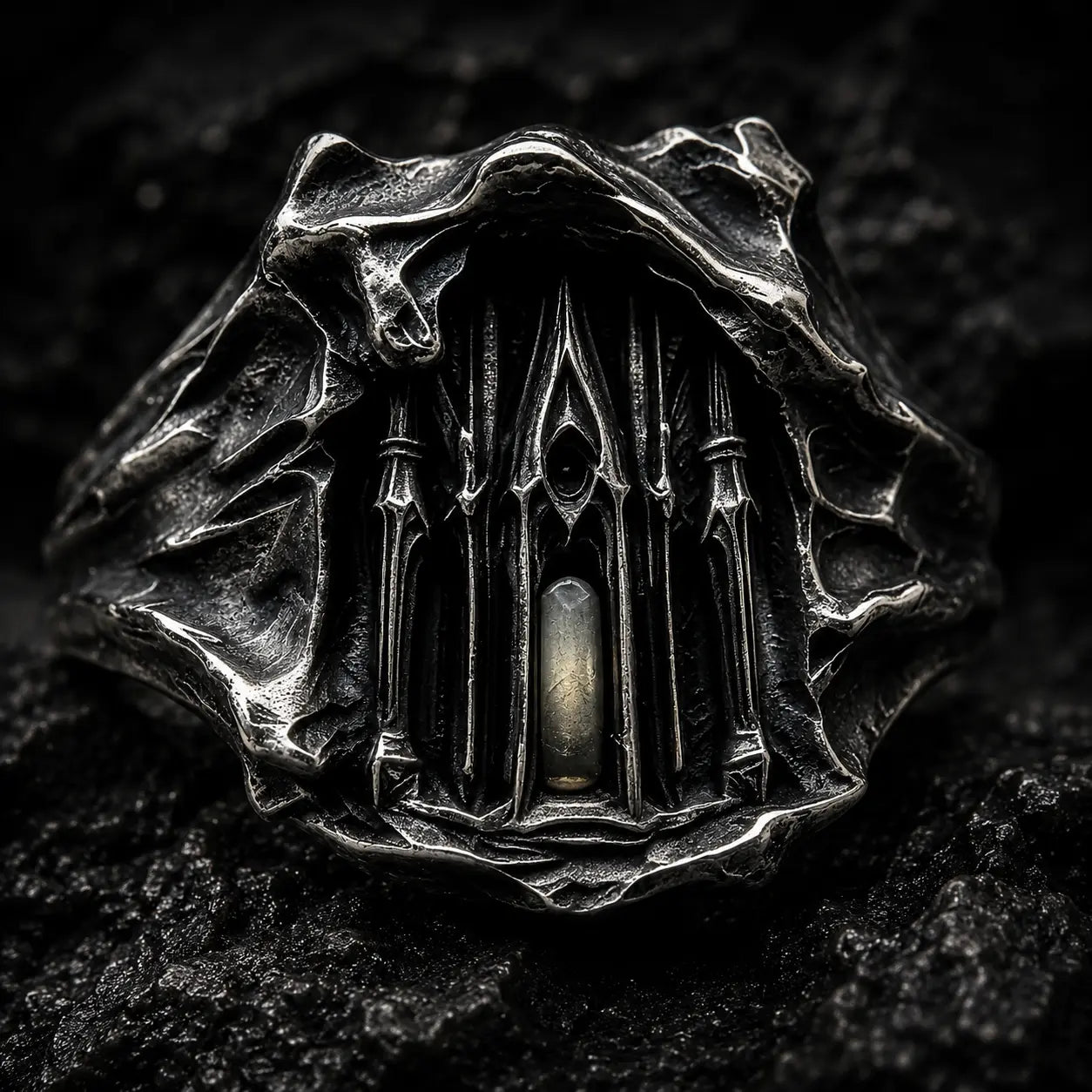 Close-up of the Dark Cathedral Ring's micro-cathedral façade with a lit central window in hand-worked silver