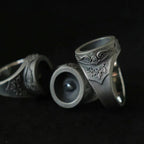 Cyclops rings showing the recessed eye pupil and rococo-baroque relief scrollwork in oxidized silver