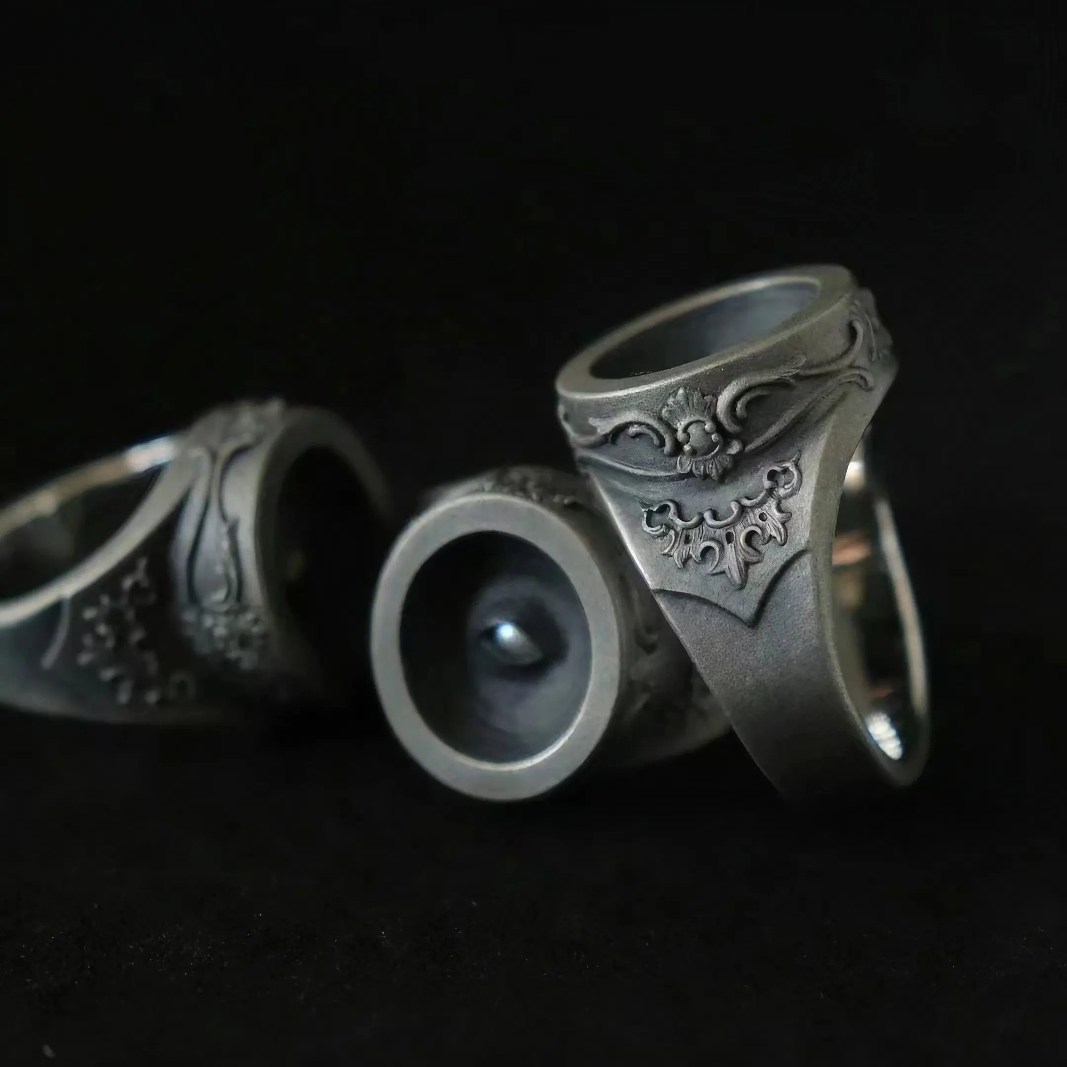 Cyclops rings showing the recessed eye pupil and rococo-baroque relief scrollwork in oxidized silver