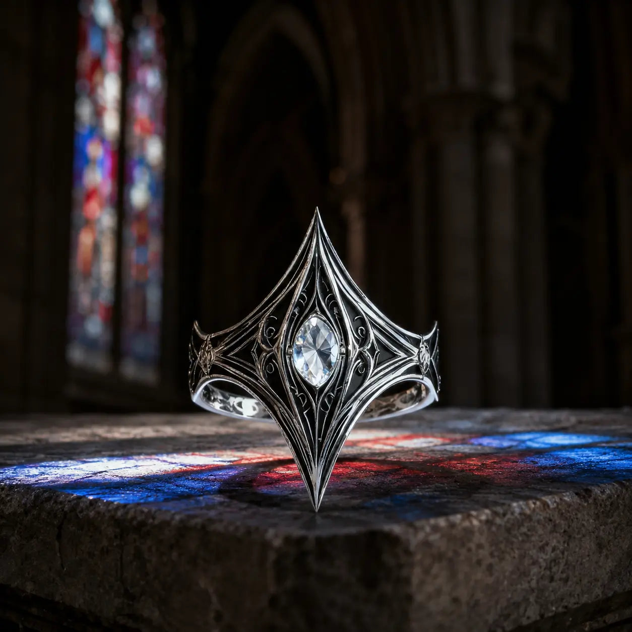 Elven Tear Ring in oxidized sterling silver with marquise moissanite, front view on a stone ledge with cathedral stained glass