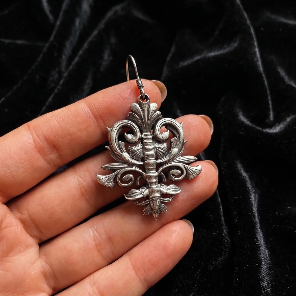 Spine motif earring held in hand showing oxidized silver detail and scale
