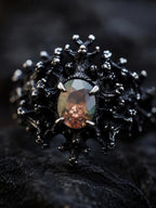 Close-up of the Dark Bloom Ring's blackened thorn-and-coral setting framing the oval gemstone