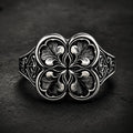Gothic clover ring — sterling silver quatrefoil engraving, front view on dark stone backdrop