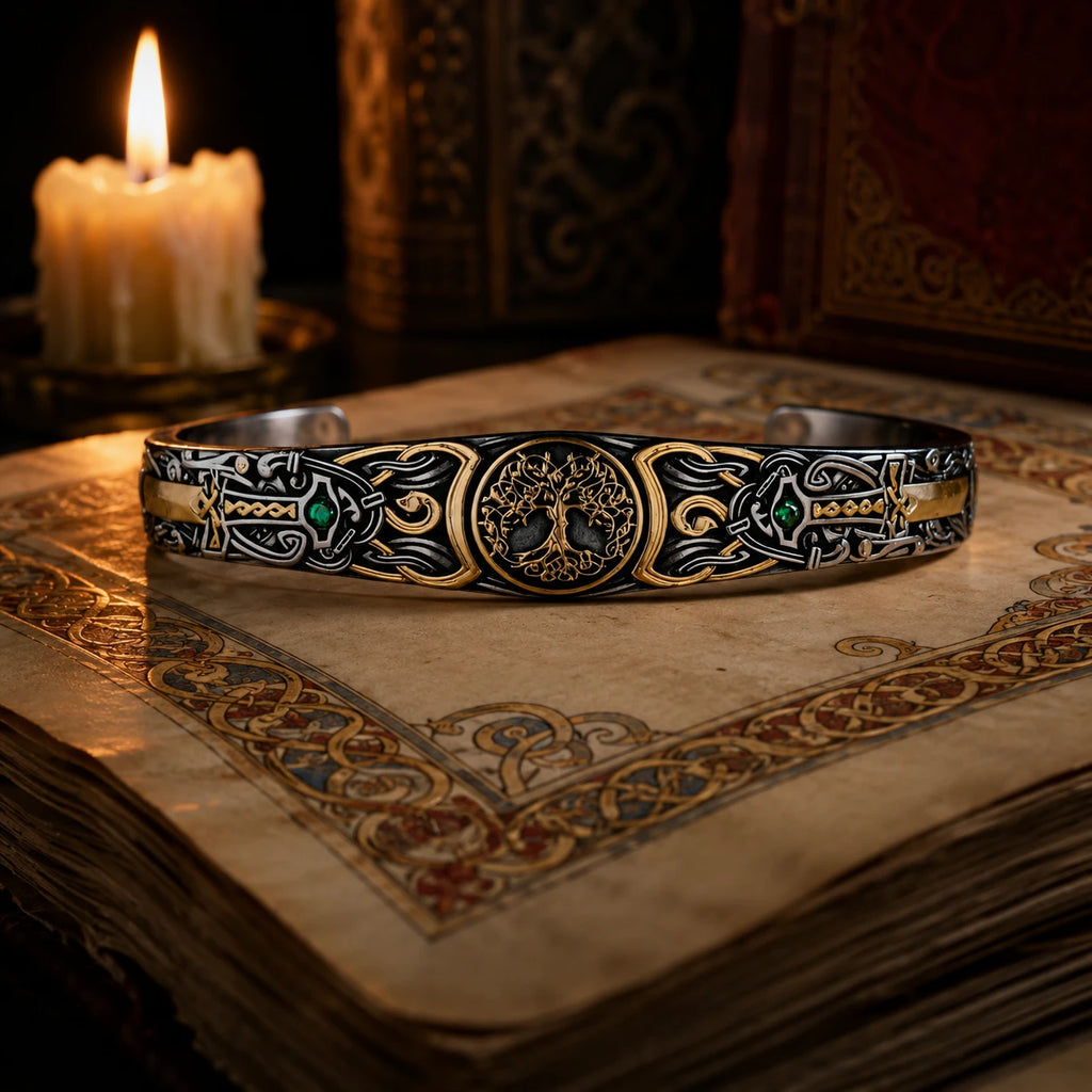 Tree of Life Celtic Cuff in oxidized 925 sterling silver with 24K gold accents and emerald stone, displayed on illuminated manuscript with candle