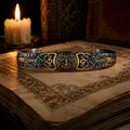 Tree of Life Celtic Cuff in oxidized 925 sterling silver with 24K gold accents and emerald stone, displayed on illuminated manuscript with candle