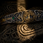 Macro detail of gold Tree of Life medallion and emerald-set sword hilt on Celtic cuff