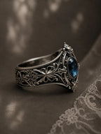Memento mori skull ring — oval-cut London blue topaz in milgrain bezel, gothic traceries in sterling silver