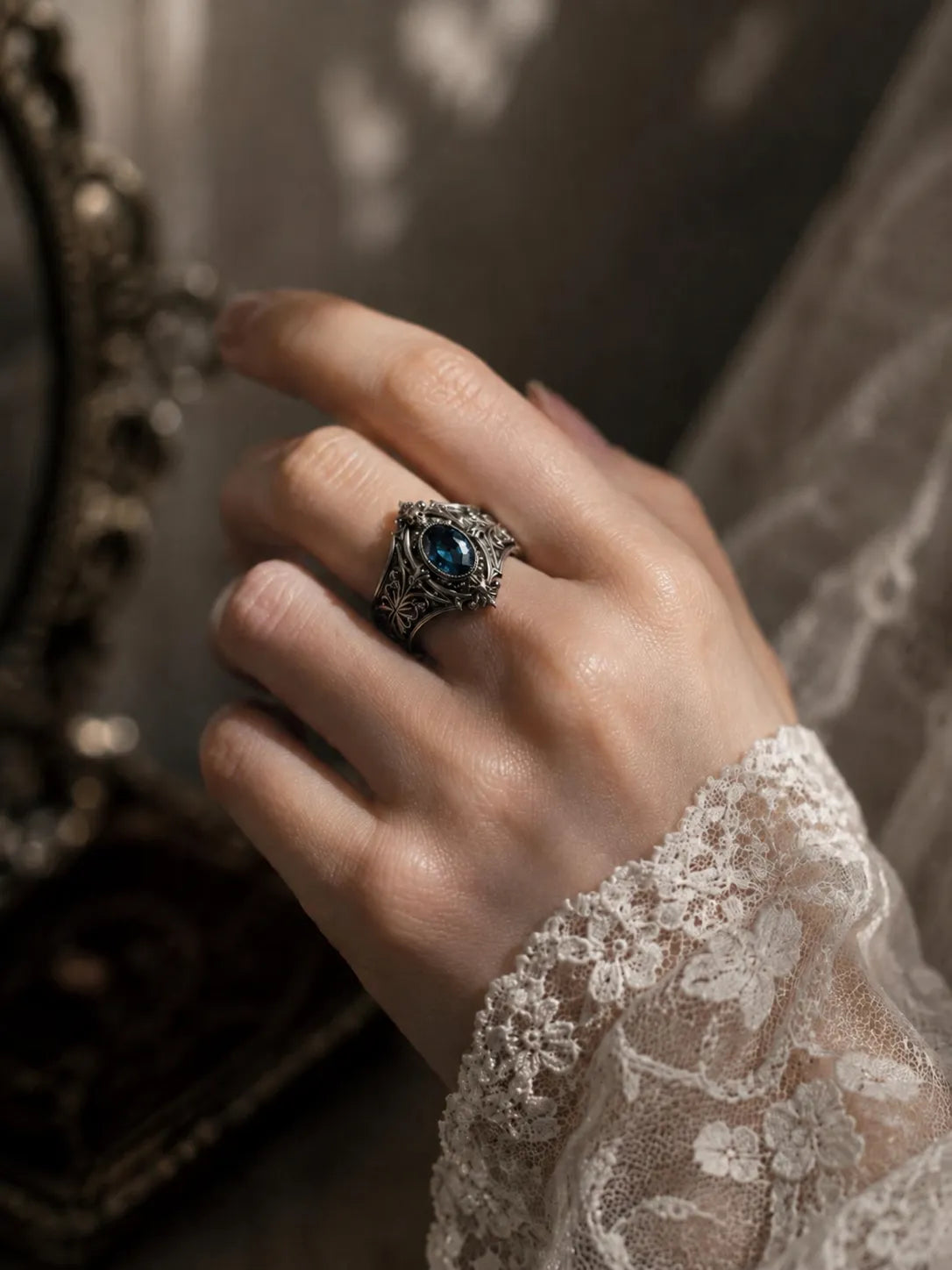 Hand wearing Victorian memento mori skull ring with blue topaz — gothic alternative engagement ring in 925 silver
