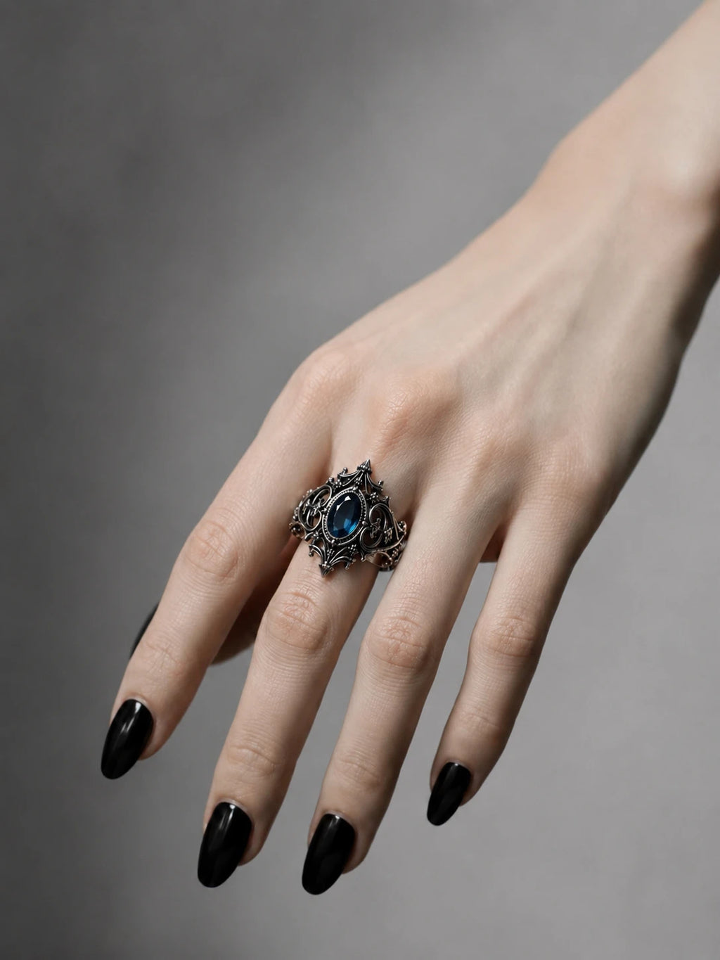 Hand wearing gothic cathedral sanctuary ring with blue topaz — alternative engagement ring in sterling silver